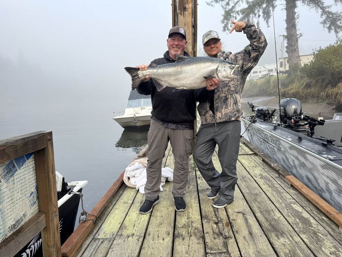 Two anglers holding a big Chinook salmon on a foggy Oregon morning